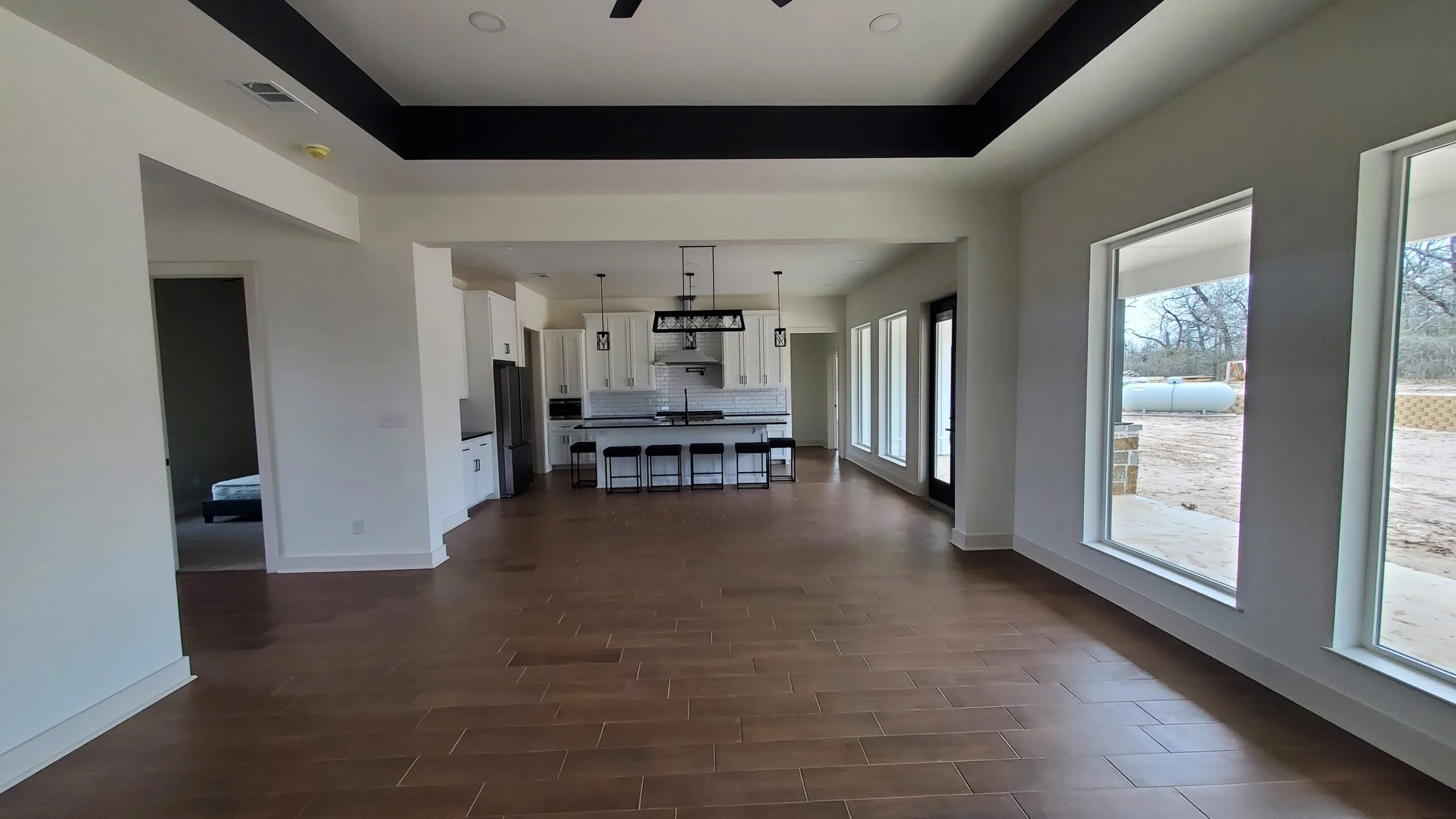Large open room with wood floors, a tray ceiling and a wall of windows