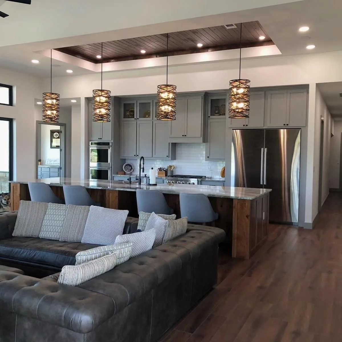 Open kitchen and living room with a long island, pendant lights and a wood ceiling