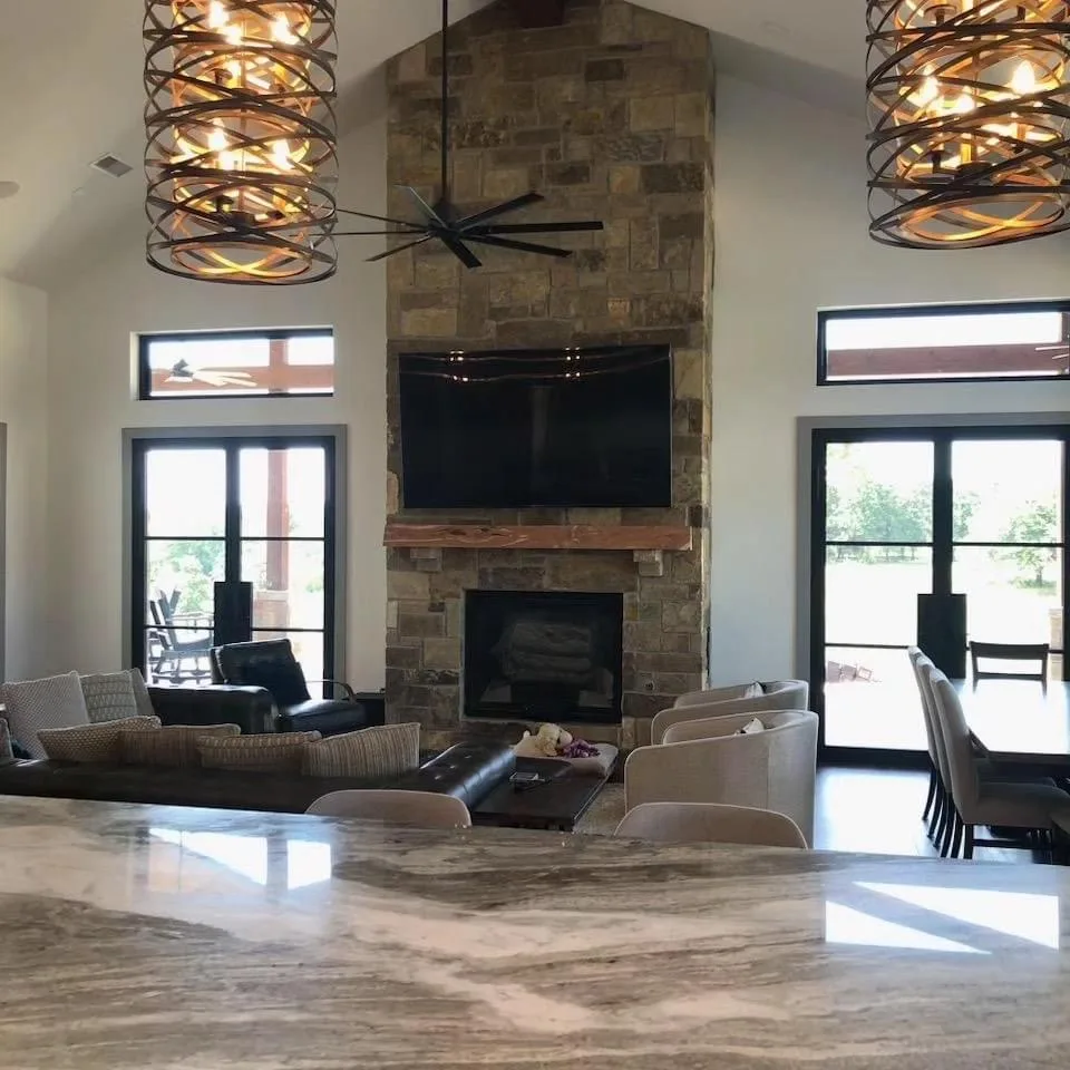 Living room with a stone fireplace and tall windows in the Lake Kiowa home