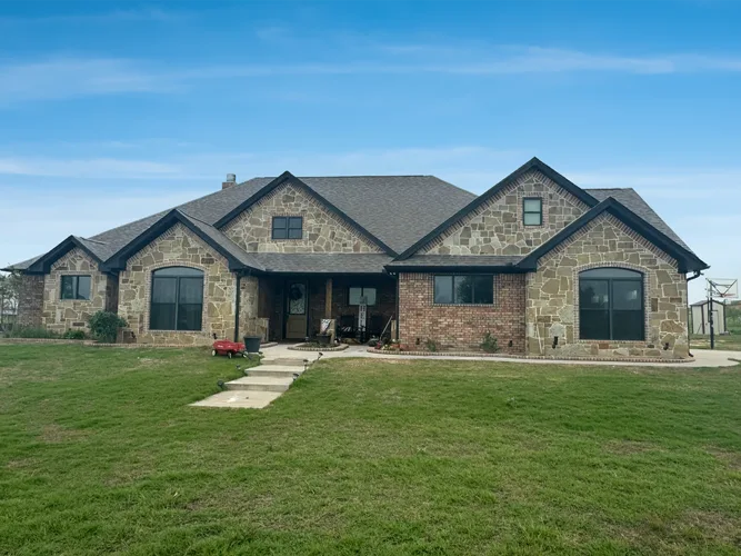Single-story stone and brick home with a green front lawn at Lake Kiowa