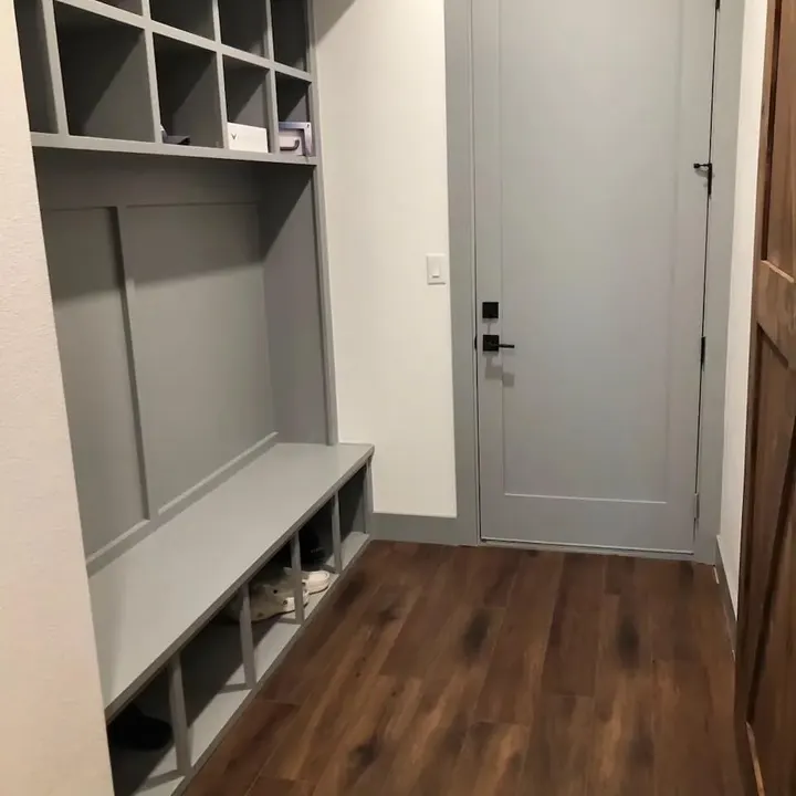 Mudroom bench with cubbies beside a gray door